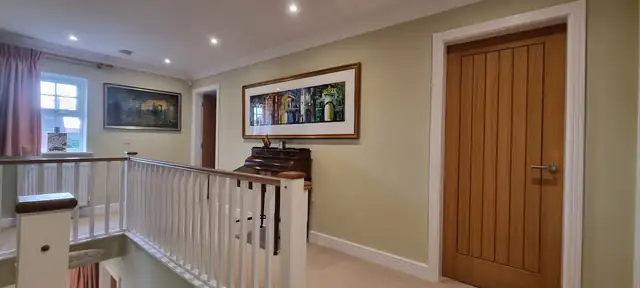 Landing with white painted spindles, cream walls and an oak door