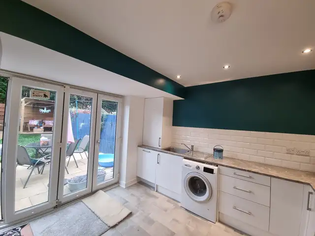 Kitchen with deep teal wall above white metro tiles and French doors