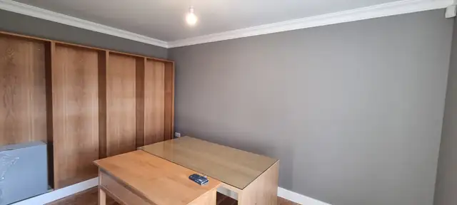 Grey room with white ceiling and coving next to oak wardrobes