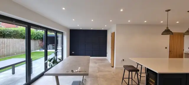 Open plan kitchen diner with white walls and a navy panelled feature wall